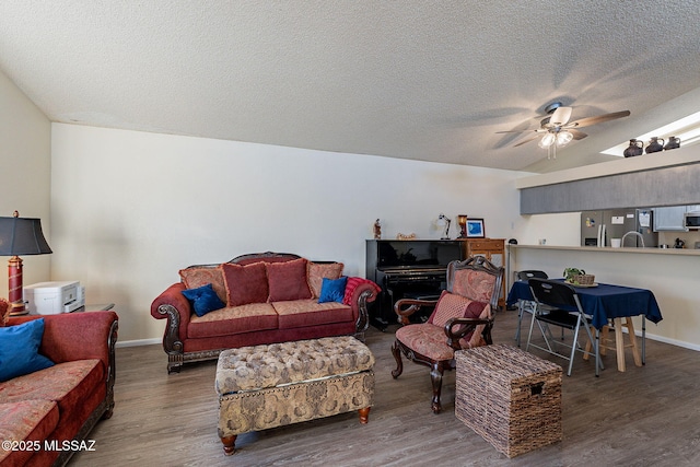 living room with ceiling fan, a textured ceiling, baseboards, and wood finished floors