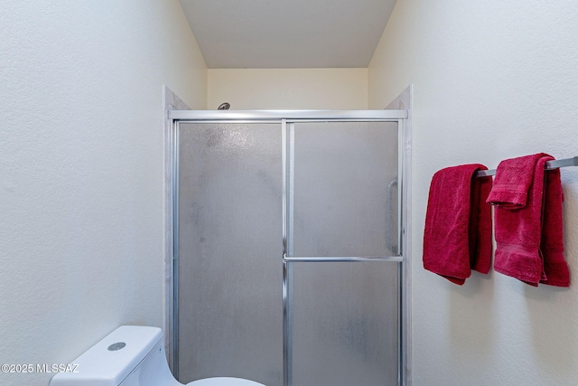 bathroom featuring toilet and a shower stall