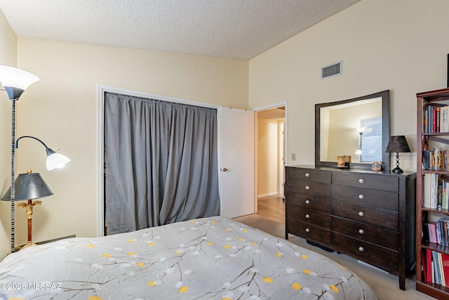 bedroom featuring visible vents, vaulted ceiling, and a textured ceiling