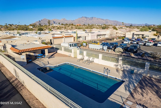 view of swimming pool featuring a patio, a residential view, fence, and a mountain view