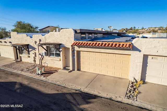 view of front of home with concrete driveway, an attached garage, and stucco siding