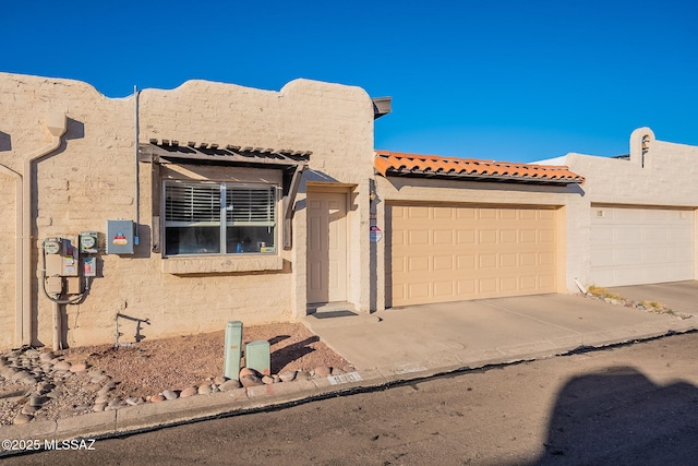 view of front facade with a garage, concrete driveway, and stucco siding