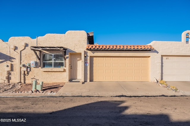 view of front of property featuring driveway, an attached garage, and stucco siding