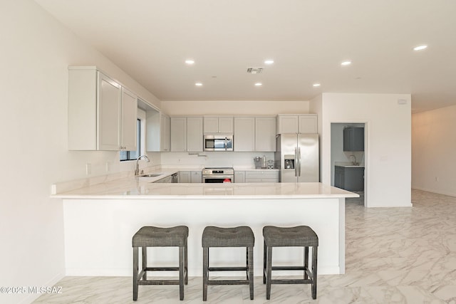 kitchen with a breakfast bar area, kitchen peninsula, sink, and stainless steel appliances