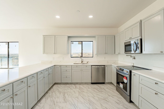 kitchen featuring kitchen peninsula, appliances with stainless steel finishes, sink, and gray cabinetry