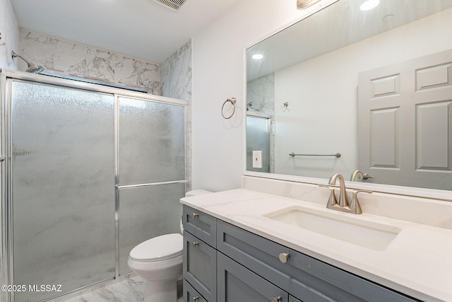 bathroom with toilet, vanity, and a shower with door