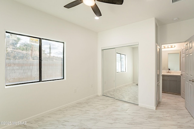 unfurnished bedroom featuring ceiling fan, sink, a closet, and ensuite bath