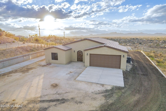 view of front facade with a mountain view, central AC unit, and a garage