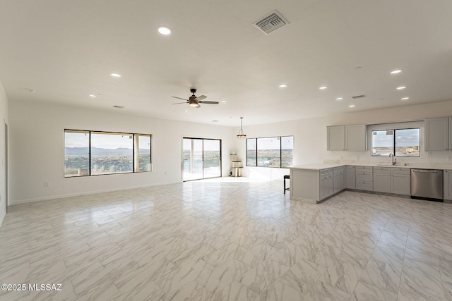 unfurnished living room featuring ceiling fan and sink