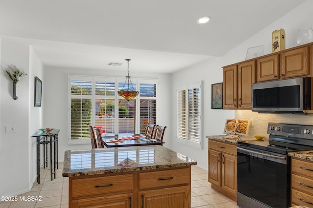 kitchen with decorative light fixtures, a kitchen island, stainless steel appliances, light tile patterned floors, and light stone counters