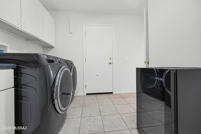 clothes washing area with cabinets, light tile patterned flooring, and washer and clothes dryer