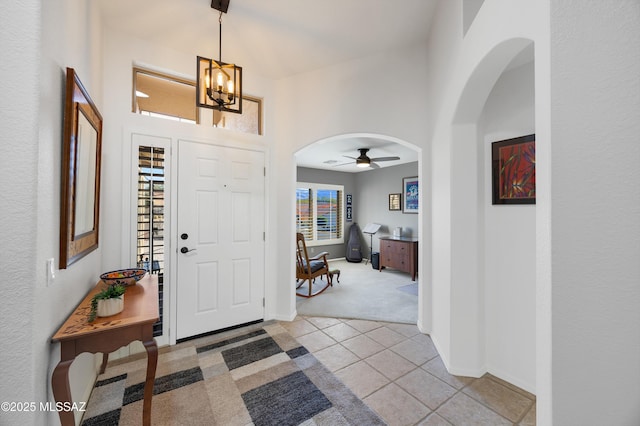 foyer with light colored carpet and ceiling fan with notable chandelier