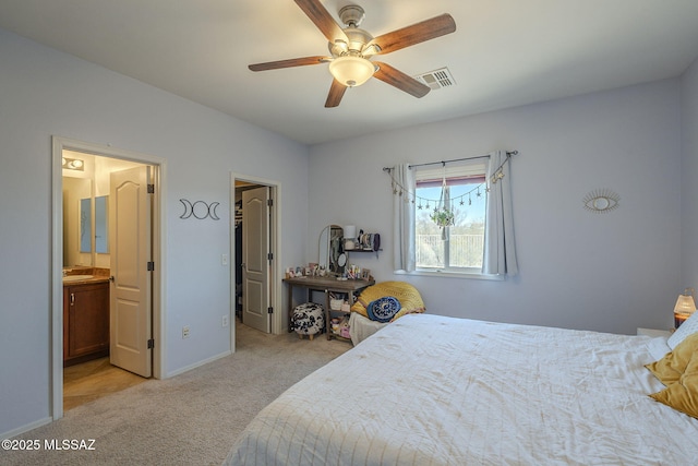 bedroom with ensuite bath, light colored carpet, and ceiling fan