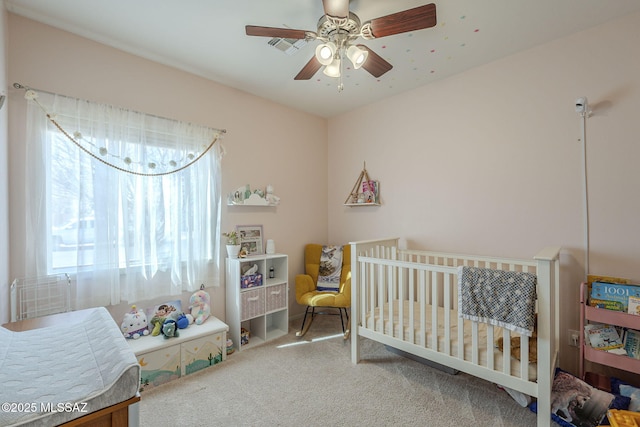 bedroom with carpet floors, a crib, and ceiling fan