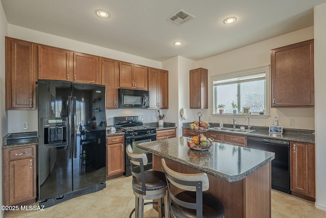 kitchen featuring sink, a kitchen bar, a center island, light tile patterned floors, and black appliances