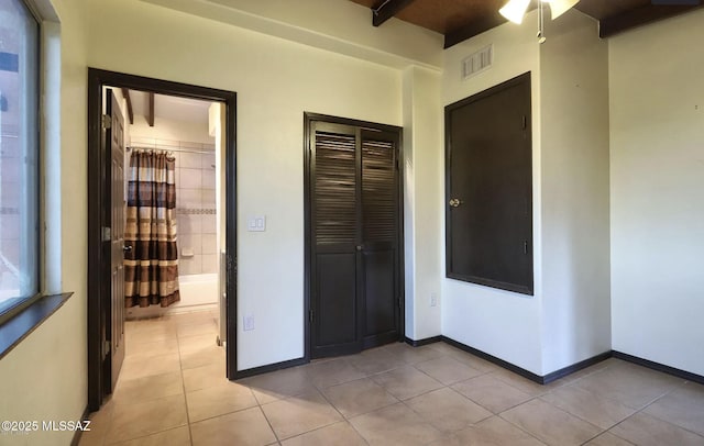 hall featuring light tile patterned flooring and beam ceiling