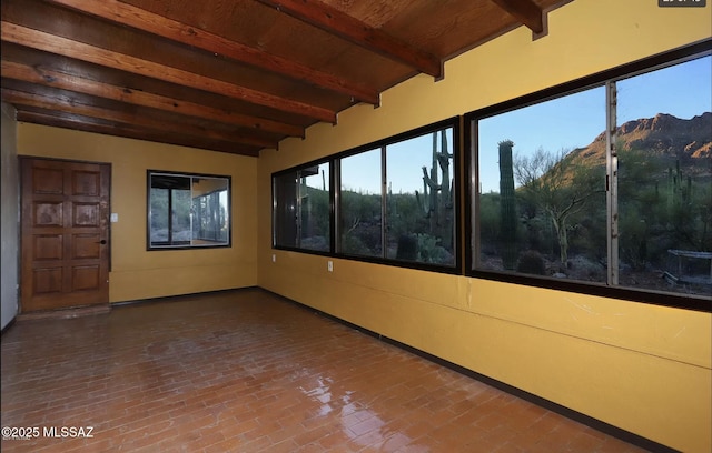 unfurnished sunroom with a mountain view, lofted ceiling with beams, and wooden ceiling