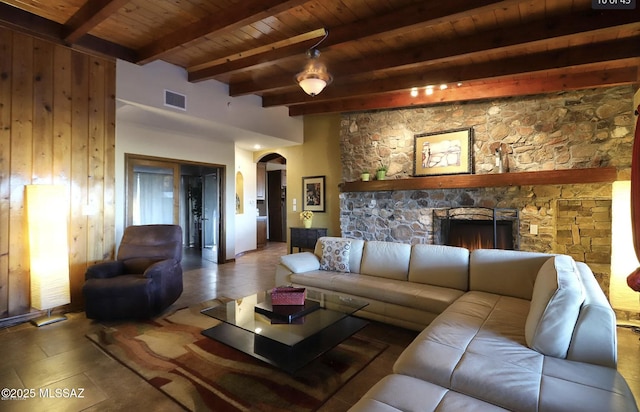 tiled living room with beam ceiling, a fireplace, wood ceiling, and wood walls