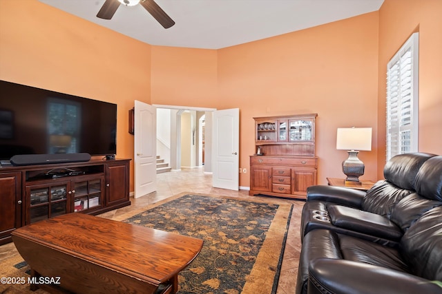 tiled living room featuring ceiling fan and a towering ceiling