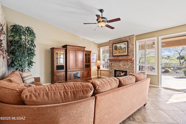 tiled living room featuring ceiling fan and a stone fireplace