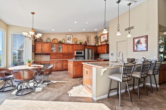 kitchen with hanging light fixtures, a kitchen island, appliances with stainless steel finishes, and a breakfast bar