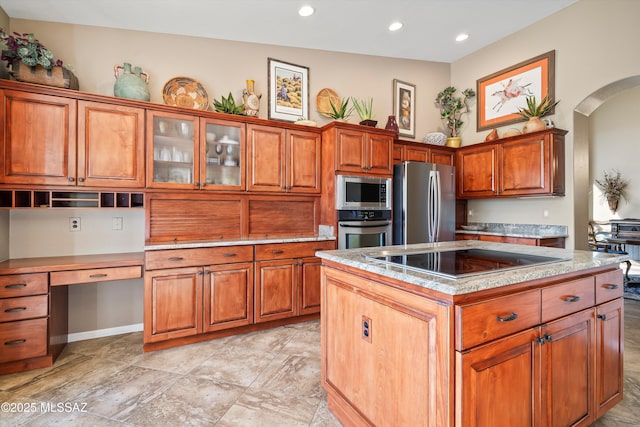kitchen featuring stainless steel appliances, a center island, a high ceiling, and built in desk