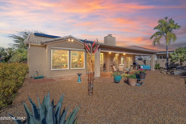 back house at dusk with a patio area