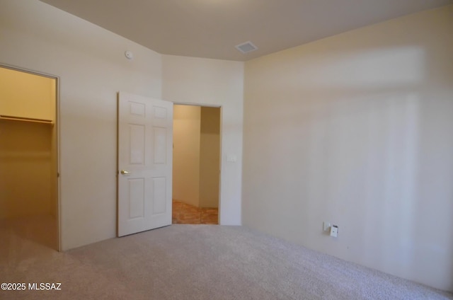 unfurnished bedroom with a spacious closet, a closet, and light colored carpet