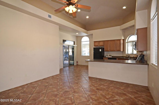 kitchen featuring tile patterned flooring, black refrigerator, sink, kitchen peninsula, and ceiling fan