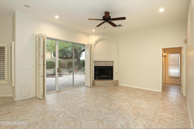 unfurnished living room featuring a tiled fireplace, light tile patterned floors, and ceiling fan