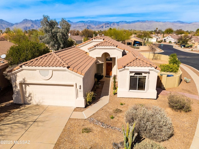 mediterranean / spanish-style home featuring driveway, a tile roof, a mountain view, and stucco siding