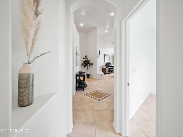 hallway featuring light tile patterned floors and arched walkways