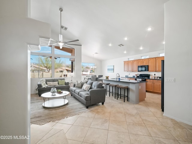 living area featuring recessed lighting, visible vents, light tile patterned flooring, high vaulted ceiling, and ceiling fan with notable chandelier