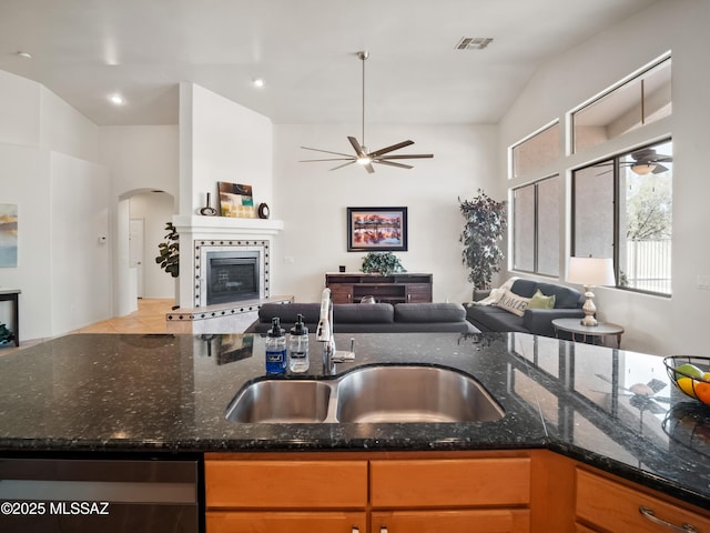 kitchen featuring open floor plan, a sink, a tiled fireplace, and ceiling fan