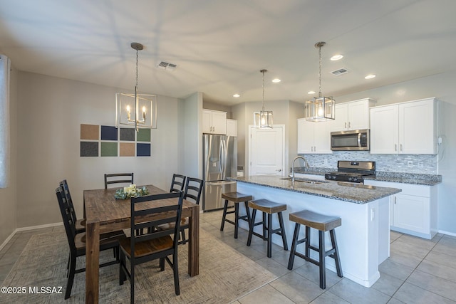 kitchen with appliances with stainless steel finishes, an island with sink, and white cabinets