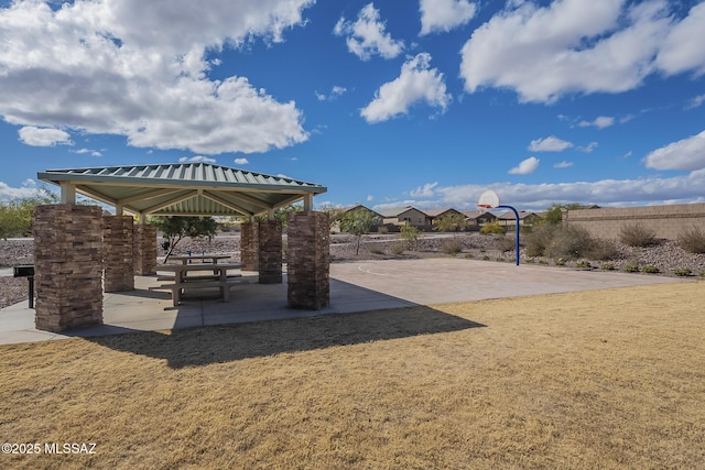 exterior space featuring a gazebo, basketball hoop, and a lawn