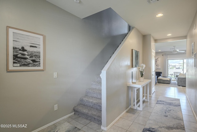 staircase with ceiling fan and tile patterned floors