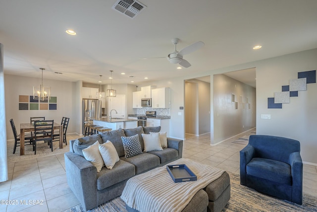 tiled living room featuring sink and ceiling fan with notable chandelier