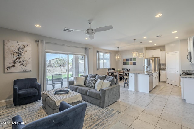 living room featuring sink, light tile patterned floors, and ceiling fan