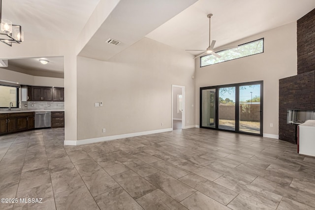 unfurnished living room with ceiling fan with notable chandelier, sink, and a high ceiling