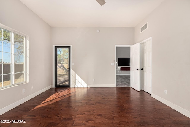 empty room featuring ceiling fan, dark hardwood / wood-style flooring, and a wealth of natural light