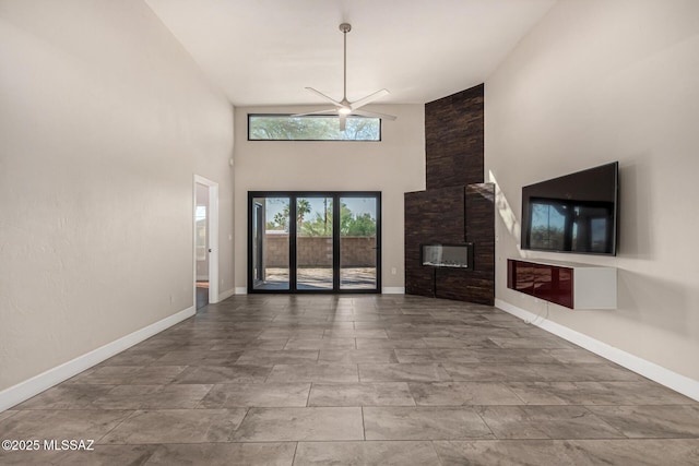 unfurnished living room with ceiling fan, a high ceiling, and a fireplace