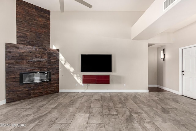 unfurnished living room with ceiling fan and a stone fireplace