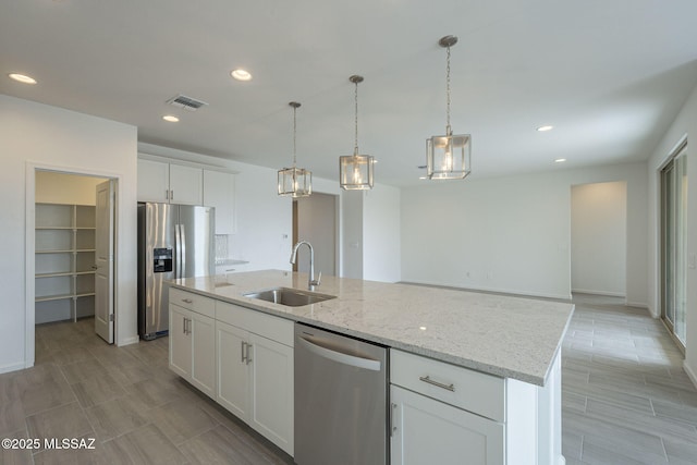 kitchen featuring sink, light stone counters, an island with sink, stainless steel appliances, and white cabinets