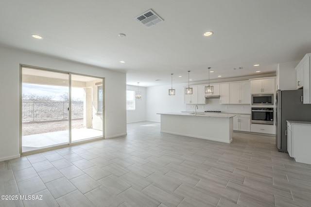 kitchen with sink, white cabinets, hanging light fixtures, a kitchen island with sink, and stainless steel appliances