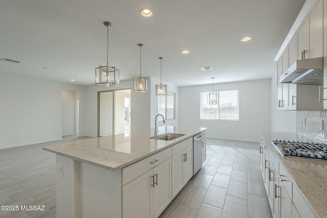 kitchen with white cabinetry, an island with sink, sink, and light stone counters