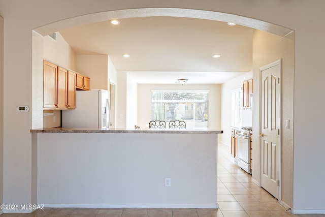 kitchen featuring light brown cabinetry, white appliances, and light tile patterned floors