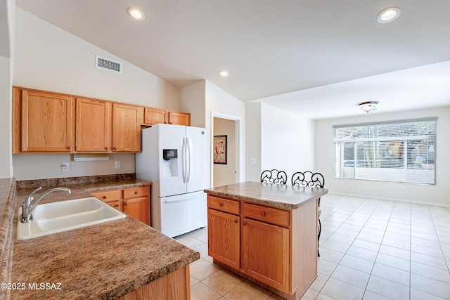 kitchen featuring light tile patterned floors, sink, lofted ceiling, white fridge with ice dispenser, and a center island