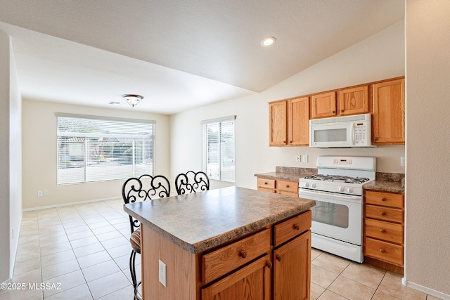 kitchen featuring vaulted ceiling, light tile patterned floors, a kitchen island, and white appliances