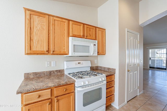 kitchen with white appliances, light tile patterned floors, and stone counters